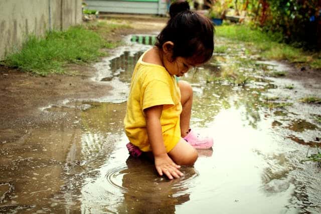 A child playing in a puddle by Robert Lee from Pexels