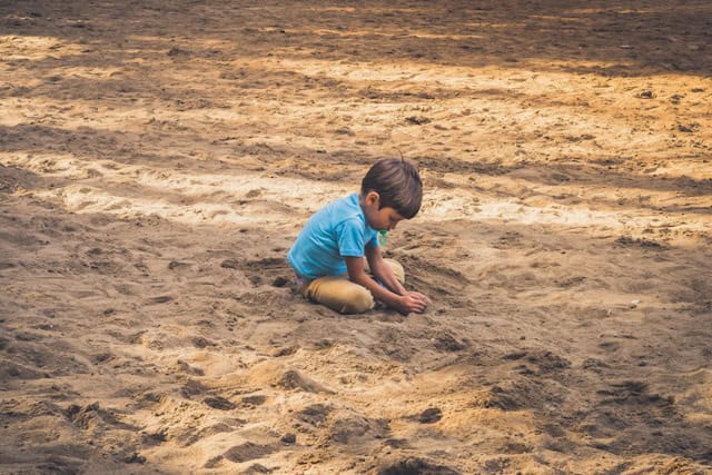 A child playing with dirt by Davidson Luna from Unsplash